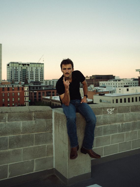 Trace Keller pointing at the camera from a rooftop wall in Boise