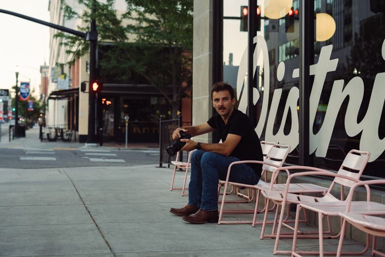 Trace Keller sitting on pink chairs outside District Coffee in Boise