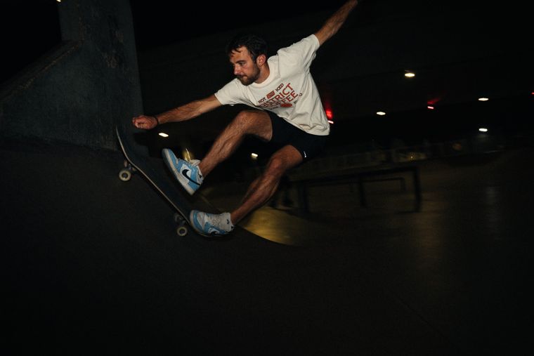 Skateboarder mid-trick at a night skate park