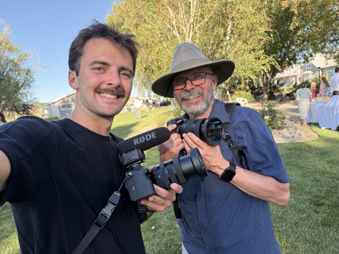 Trace Keller taking a selfie with an older photographer, both holding cameras at a wedding