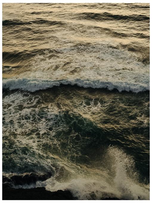 Overhead view of crashing waves and spray on dark rocks