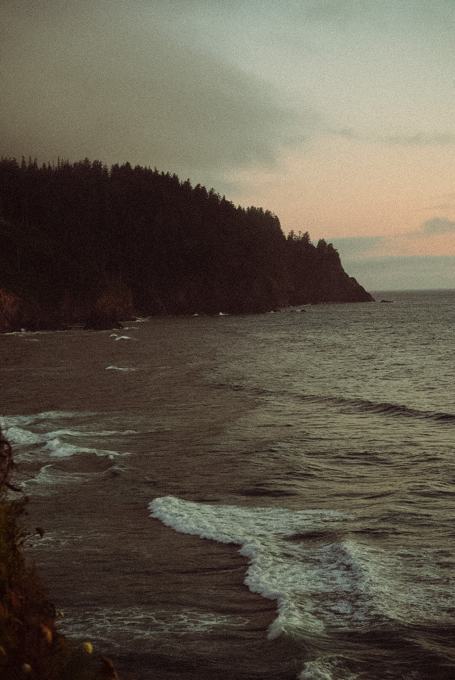 Moody coastal headland with waves rolling in at dusk