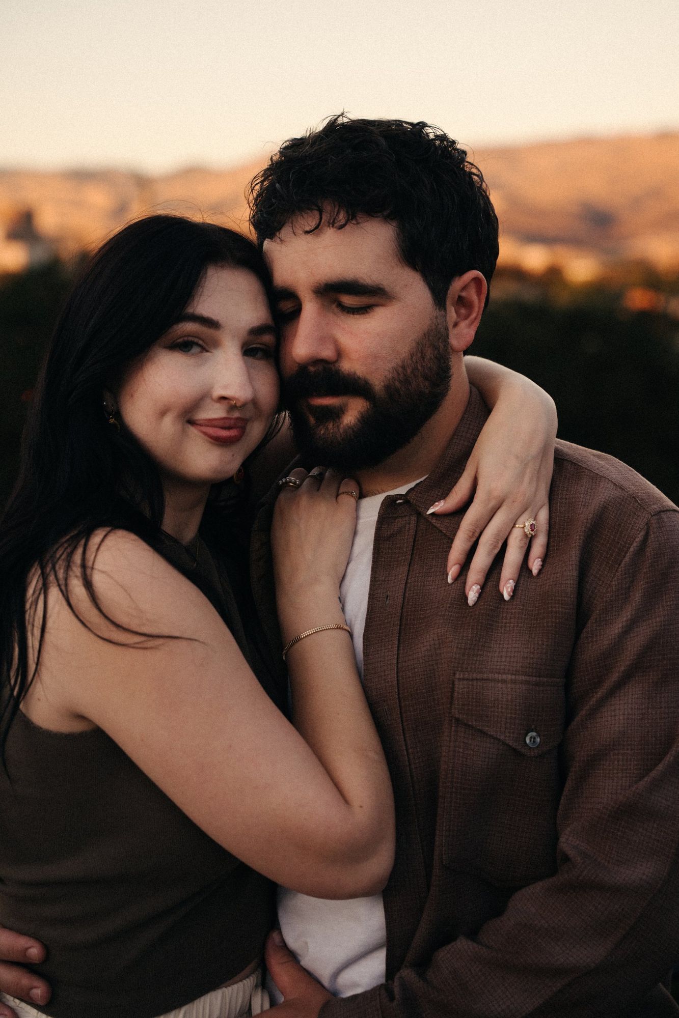 Portrait of James and Cora embracing at golden hour with the Boise foothills glowing behind them