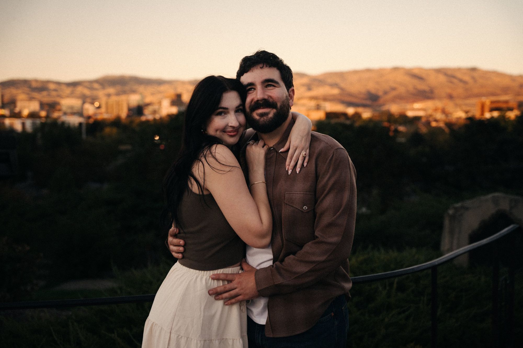 James and Cora hugging at sunset with downtown Boise and the foothills glowing behind them