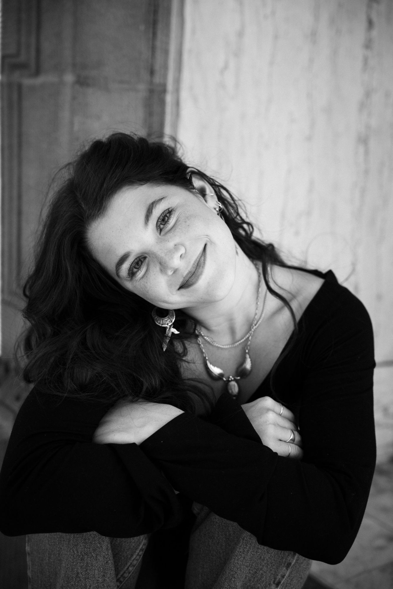 Adeline resting her head on her folded arms and smiling at the camera in black and white