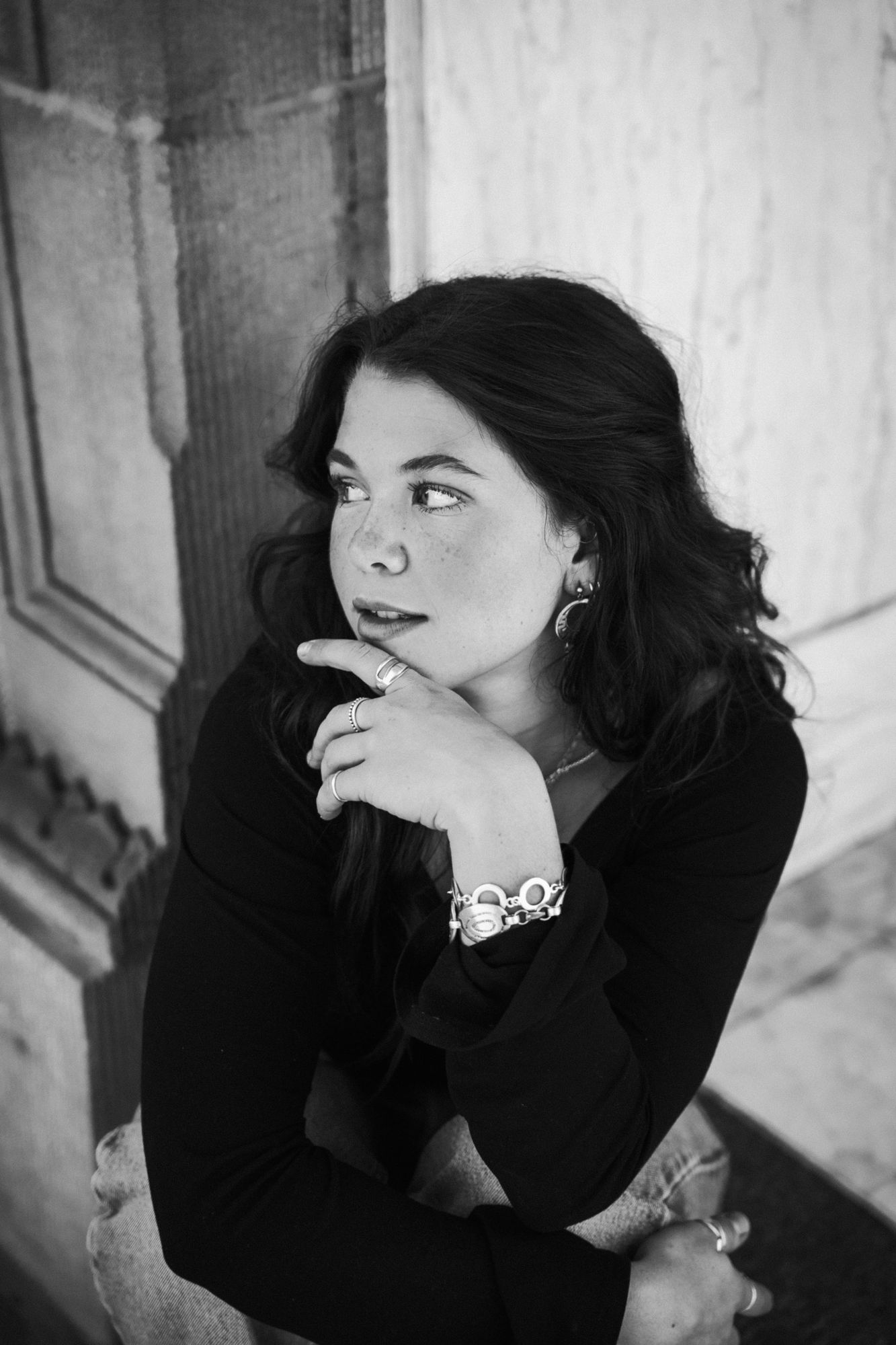 Adeline looking off to the side in black and white, her hand at her chin and a silver bracelet on her wrist