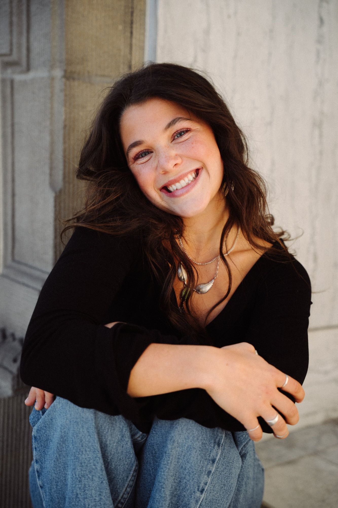 Adeline with a big smile and her arms resting on her knees, hair blowing slightly