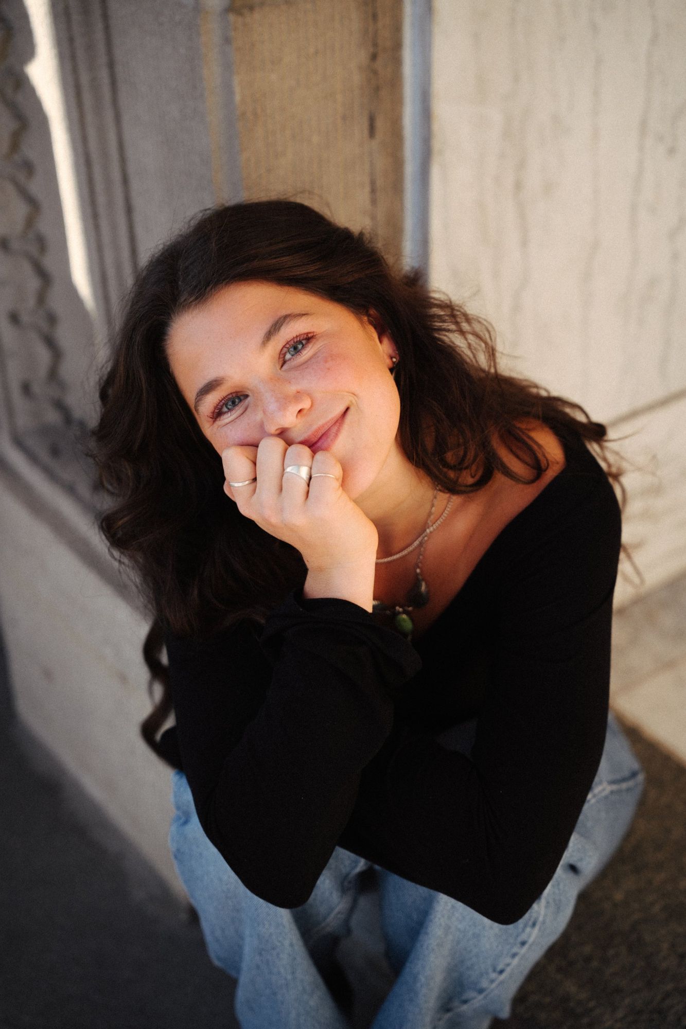 Adeline smiling up at the camera with her chin on her hand, silver rings on her fingers