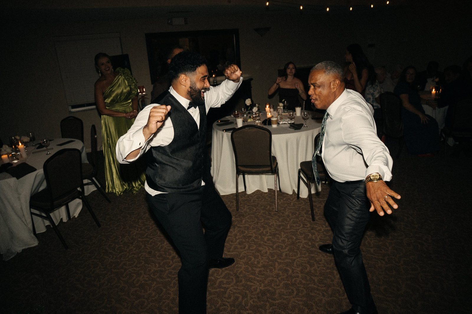Caio dancing with an older guest on the reception dance floor while family watches and smiles