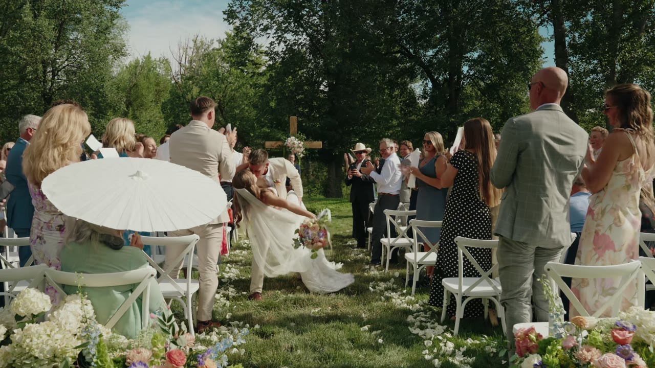 Cam and Kennedy share a kiss and dip in the aisle as guests cheer at their wedding in Eagle, Idaho