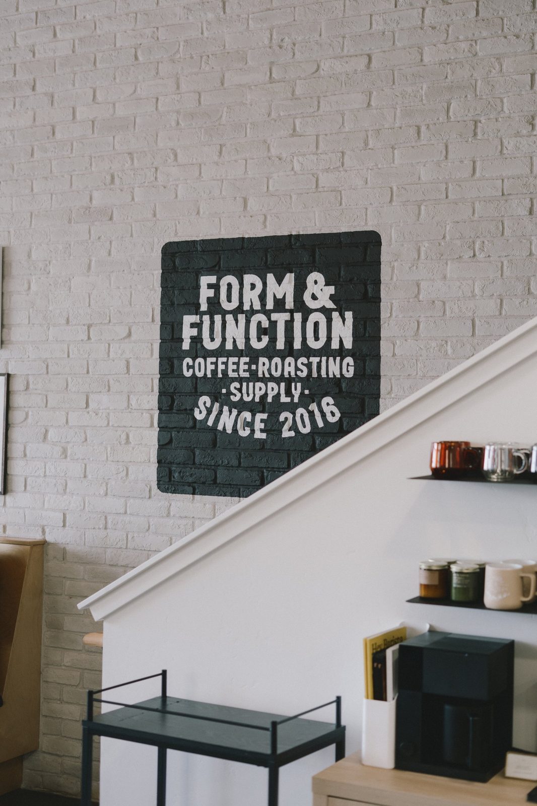 Painted Form & Function Coffee Roasting Supply sign, since 2016, on a white brick wall above a staircase