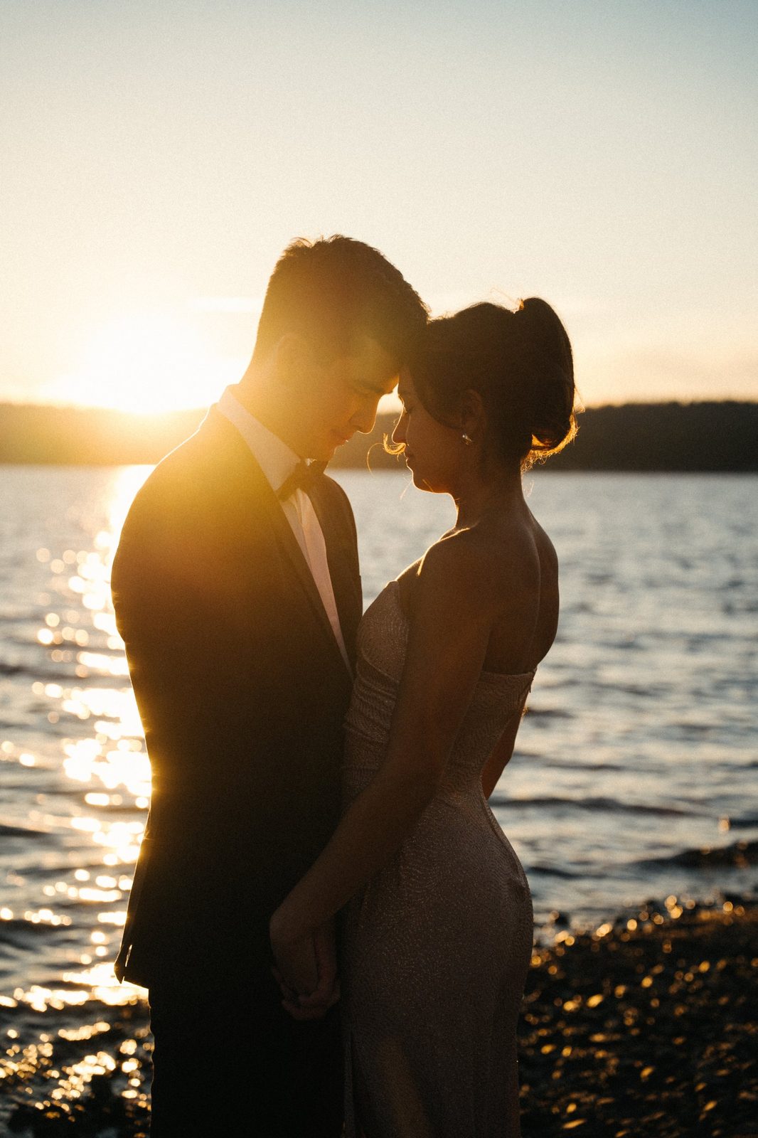 Skyler and Becca in silhouette forehead to forehead as the sun sets over the lake in McCall, Idaho