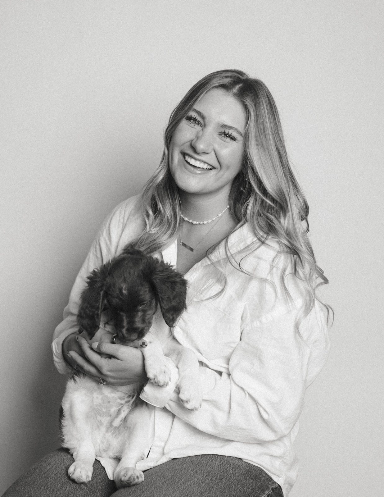 Black and white portrait of a woman laughing while holding a sleepy springer spaniel puppy in her lap
