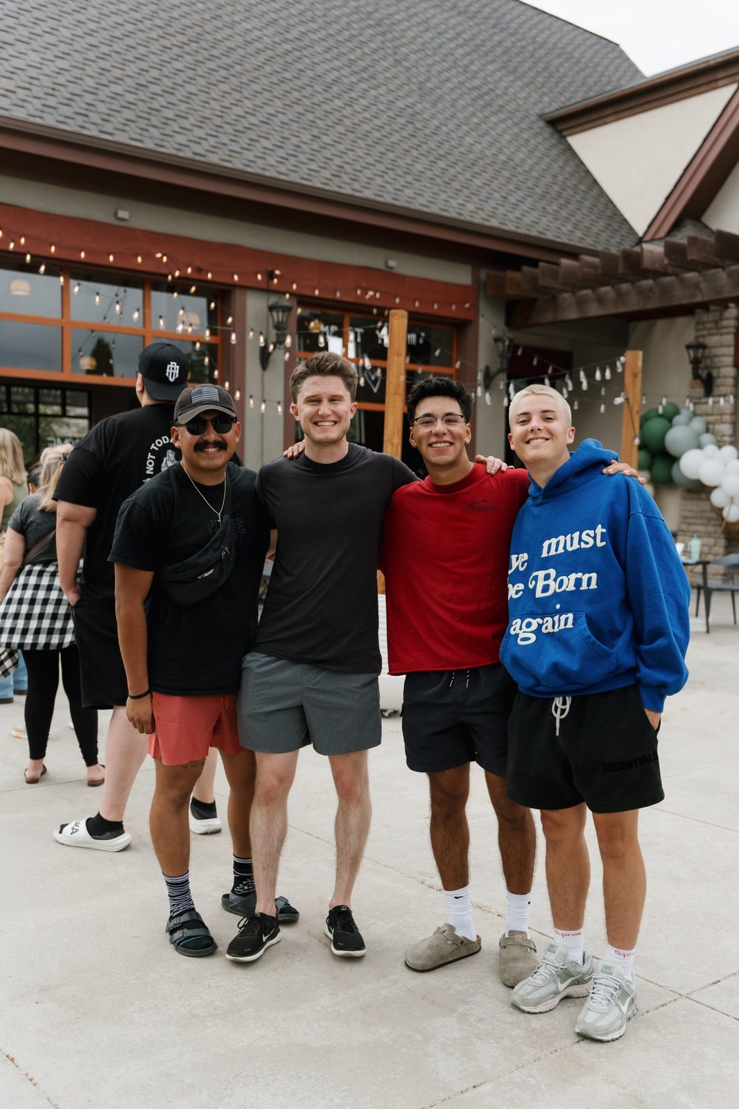 Four smiling young men with their arms around each other on the patio outside Salt & Light Coffee Lounge