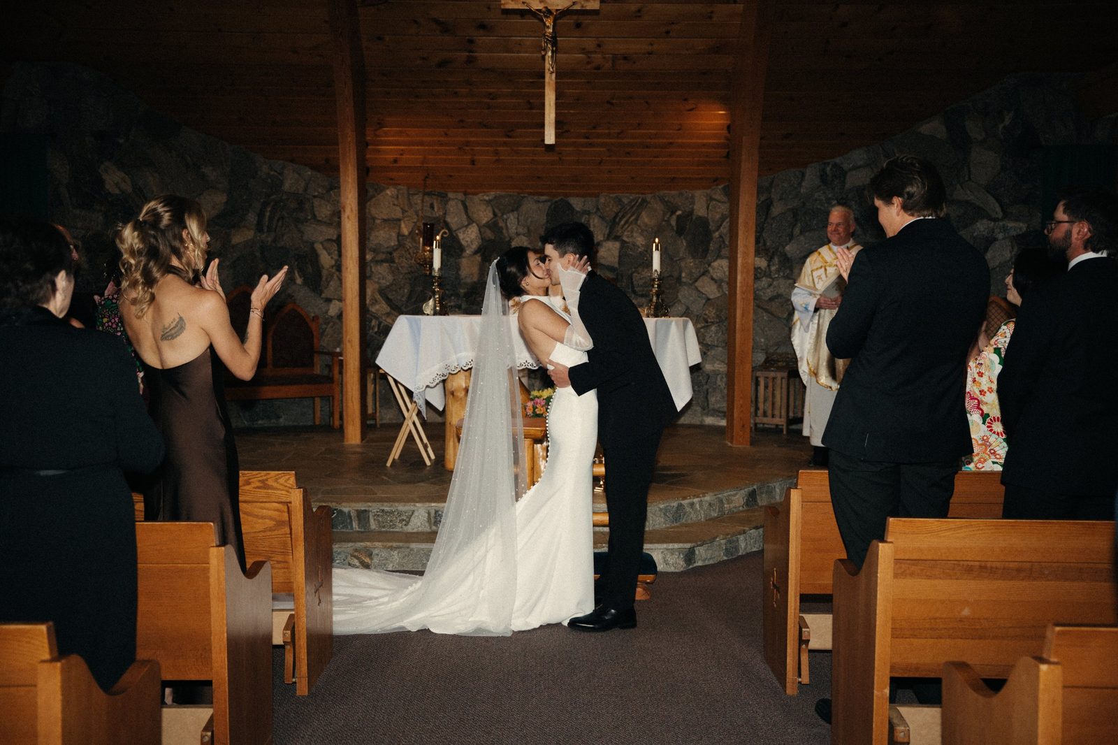 Skyler and Becca share their first kiss at the altar of a wood and stone chapel in McCall, Idaho, as guests applaud